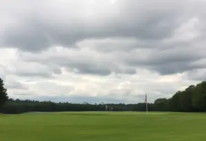 Golf course view showing empty fairways and cloudy skies hinting at postponed tournament