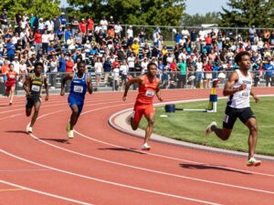 Athletes competing at the University of Houston Track & Field event with spectators cheering.