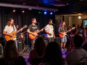 A diverse group of musicians performing live on stage with a lively audience.