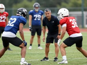 Mentorship between an experienced athlete and a college player during football practice.