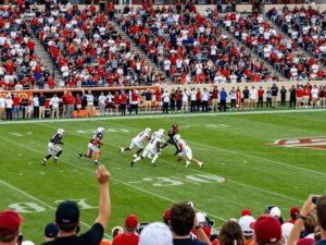 Texas college football game with players on the field and fans cheering.