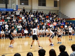 Players competing in a high school basketball game with crowd support