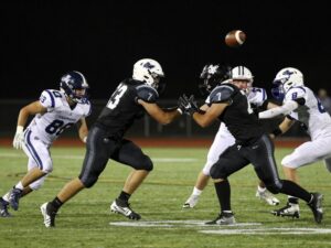 Players in action during a high school football game under stadium lights