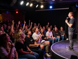Comedian Adam Mamawala performing in a packed comedy club