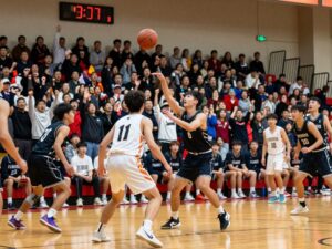 High school basketball players competing in a game with spectators in the background.